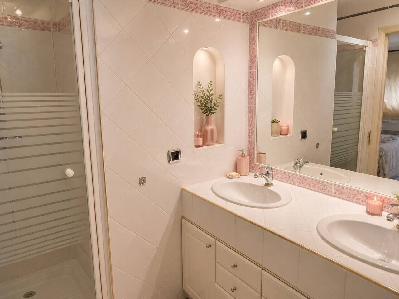 A bathroom with two sinks, a mirror, and a shower.