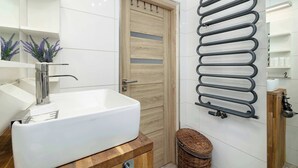 A bathroom with a white sink, wooden door, and a towel rack. - Bright Studio in Center | Desk | Close to the Park (Kraków)