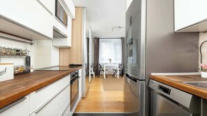 A modern kitchen with a wooden countertop, stainless steel appliances, and a dining area with a table and chairs. - Bright Studio in Center | Desk | Close to the Park (Kraków)