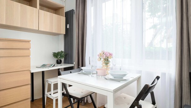 A modern kitchen with white cabinetry, a dining table, and chairs. - Bright Studio in Center | Desk | Close to the Park (Kraków)
