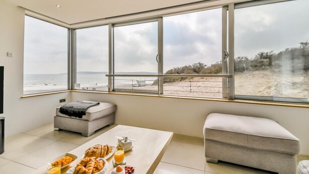 Ein modernes Zimmer mit großen Fenstern, einem Esstisch mit Frühstück und einer gemütlichen Sitzecke.