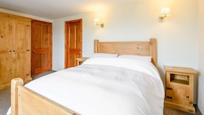 Ein Schlafzimmer mit einem hölzernen Bett, zwei Nachttischen, einem Kleiderschrank und Wandleuchten.