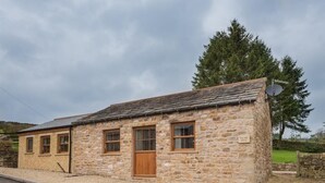 Un bâtiment en pierre avec un toit en pente, une porte en bois et une antenne parabolique.