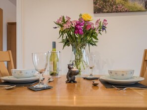 Ein Esstisch mit Blumen in einer Vase, Weingläsern und einem Kerzenhalter.