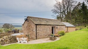 Une charmante maison en pierre avec un petit patio, un banc en bois et une vue sur la campagne.