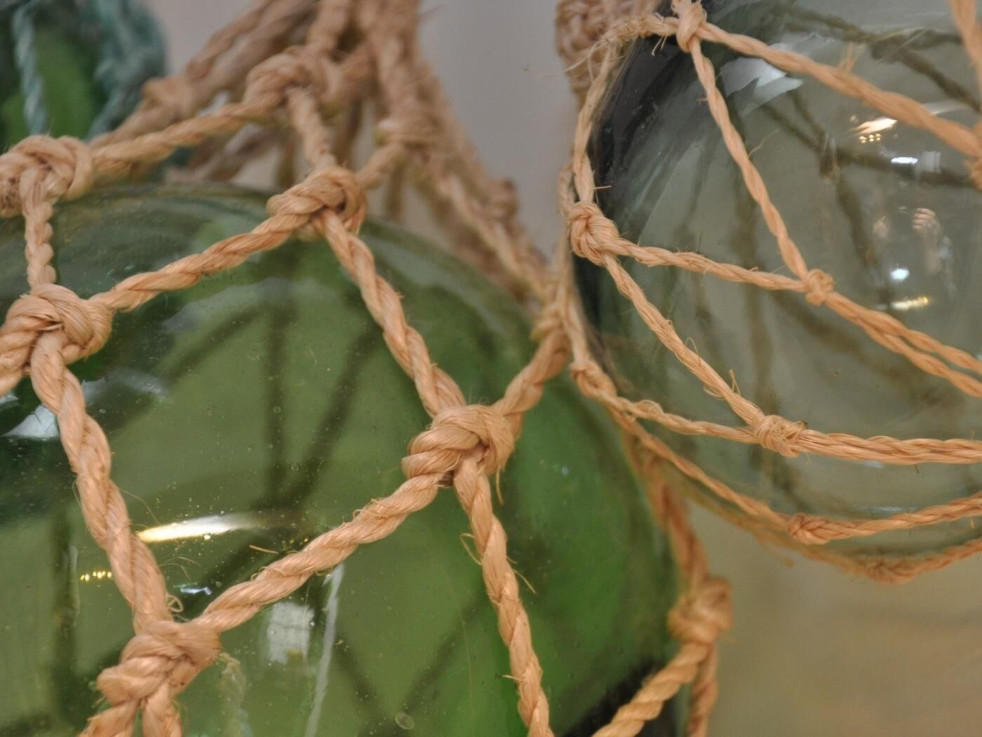 A close-up of a rope-woven structure with green glass objects.