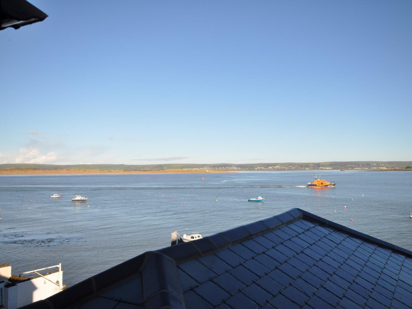 Une vue sur la côte, avec des bateaux sur l’eau, un ciel dégagé et une ligne de rivage lointaine.