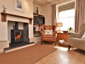 Ein gemütliches Wohnzimmer mit Kamin, Ledersessel, gestreifter Couch und Holzböden.