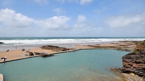 Un paysage côtier avec une piscine, une plage et des falaises rocheuses.