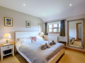 A hotel room with a bed, bedside tables, a window with curtains, a radiator, a mirror, and framed pictures on the wall. - 1 Bed in Beaulieu Heath (oc-nfl87) (Holbury)
