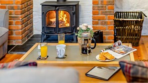 Een gezellige kamer met een met baksteen beklede open haard, een bijzettafeltje met ontbijtartikelen, en een rieten mand.