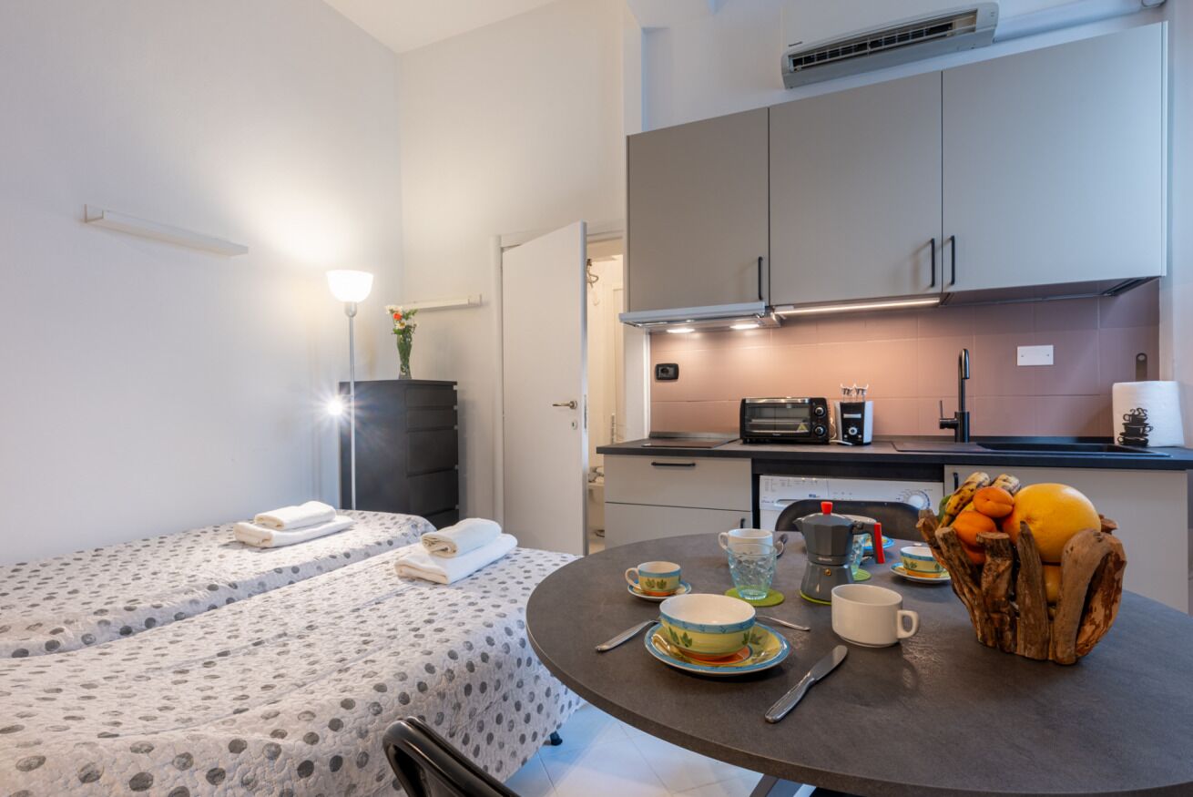 Une chambre d’hôtel de taille réduite, comprenant un lit, une petite table à manger, un coin cuisine et une salle de bain.