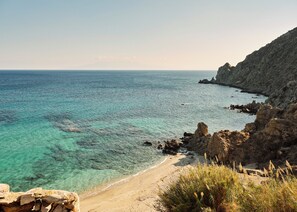 Un paisaje costero con aguas turquesas cristalinas, acantilados rocosos y una playa arenosa.