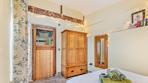 A bedroom with a bed, a wooden wardrobe, a mirror, and string lights. - 1 Bed in Bideford (oc-gatab) (Bideford)