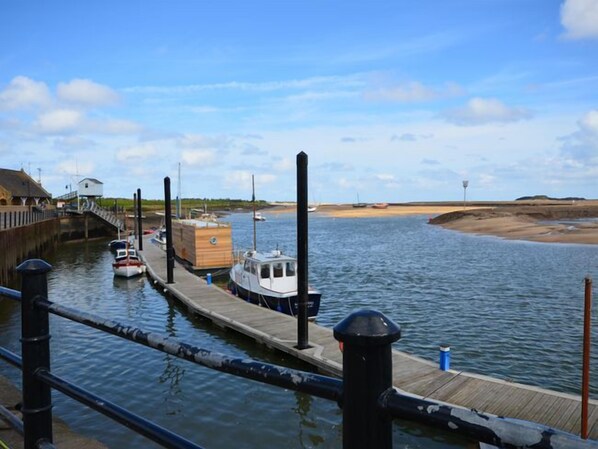 A calm waterway with a dock, a small boat, and a wooden building.