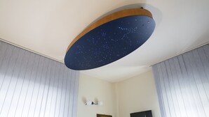 Une pièce dont le plafond est décoré de motifs représentant des étoiles, avec un téléviseur fixé au mur et un miroir encadré.