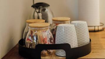 Una bandeja con frascos y tazas sobre una superficie de madera, un rollo de toallas de papel y un cartel de no fumar en la pared.