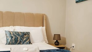 Ein Bett mit Kopfteil, Kissen, Decke, einer Nachttischlampe und einer Steckdose.
