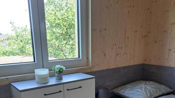 A bedroom with a window, a bed, a bedside table, and a wardrobe.