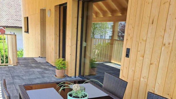 An outdoor patio with a wooden table and chairs, potted plants, and a glass door leading to a covered area. - Apartment 'Ferienappartement Coleen' with Private Terrace, Balcony and Wi-Fi (Höchst)