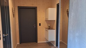 A hallway with wooden walls and floors, a dark door, a white cabinet, and a mirror. - Apartment 'Ferienappartement Coleen' with Private Terrace, Balcony and Wi-Fi (Höchst)