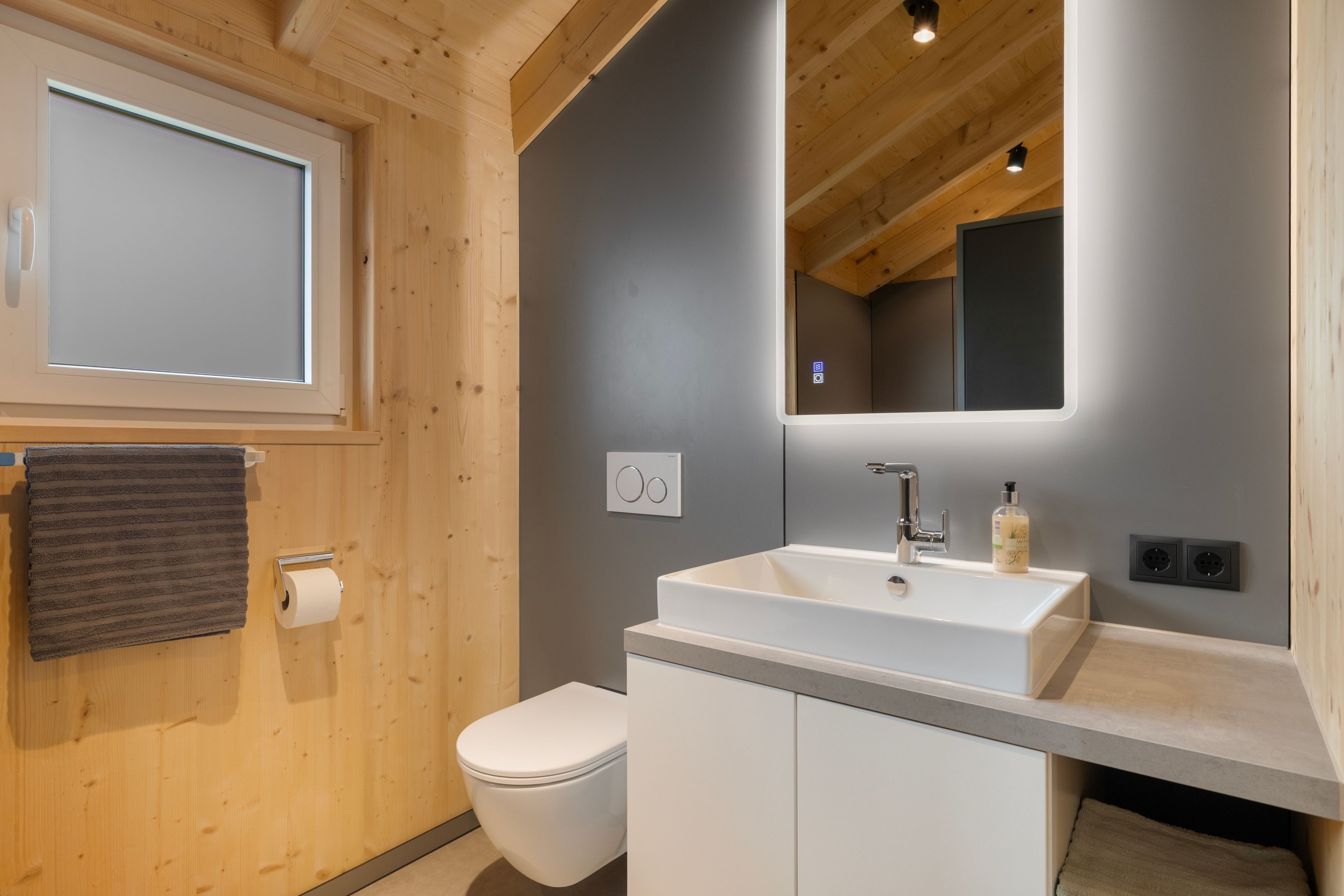 Een moderne badkamer met toilet, wastafel en spiegel.