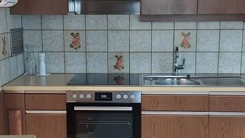 Eine moderne Küche mit Holzschränken, einer Edelstahl-Dunstabzugshaube, einem eingebauten Backofen und einer mit Tiermotiven versehenen Küchenrückwand.
