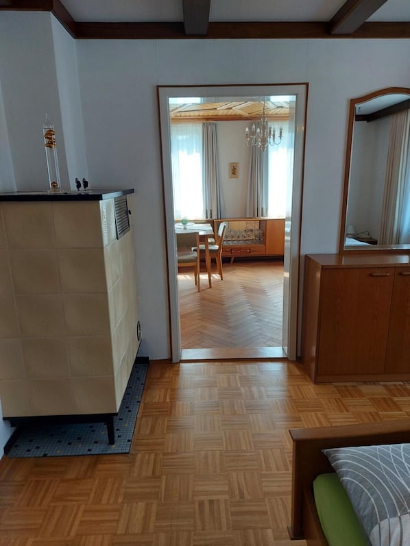 A room with a wooden floor, a bed with a green pillow, a dresser, and a mirror.