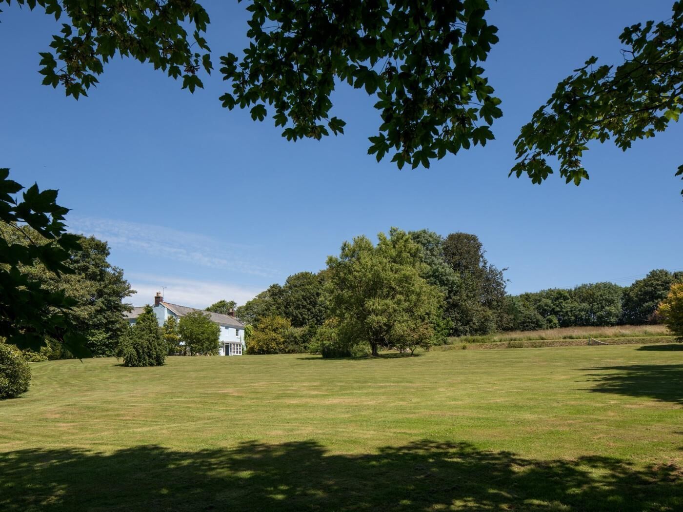 A grassy field with trees and a white building.