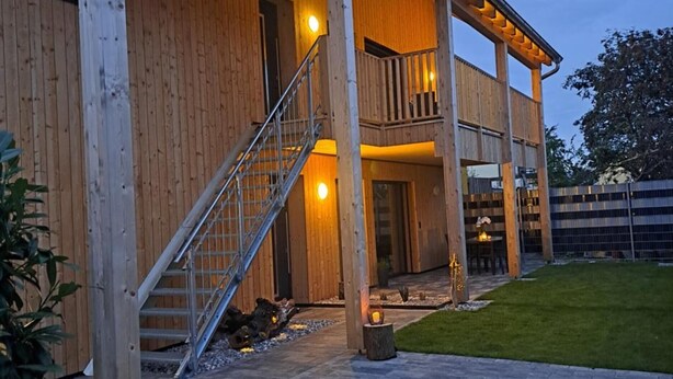 Un edificio in legno con un’area esterna coperta, una scala e un patio lastricato.