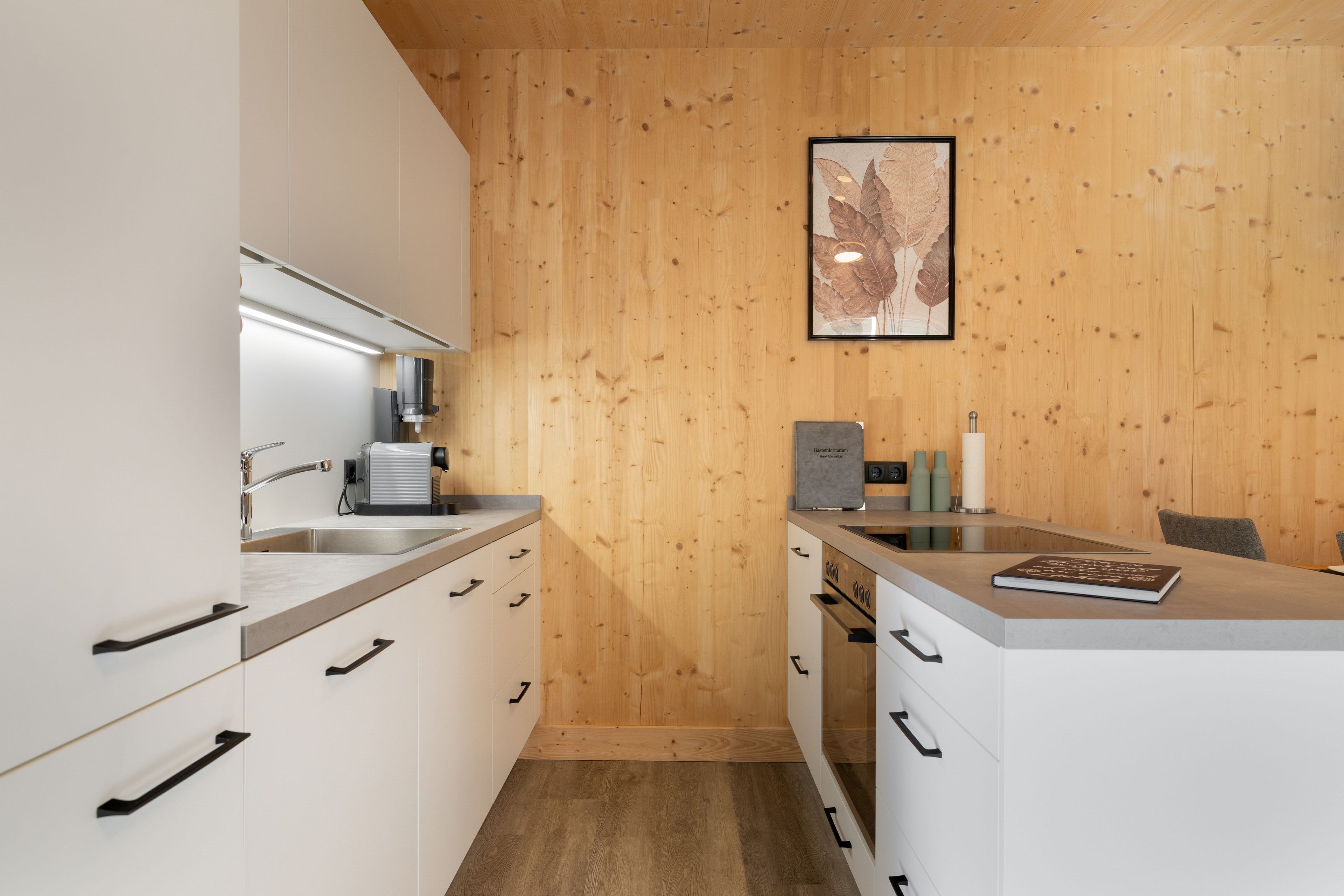 Una cocina moderna con paneles de madera, electrodomésticos de acero inoxidable y una obra enmarcada sobre la encimera.