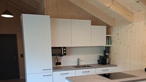Una cucina moderna con mobili bianchi, un'isola centrale e un soffitto in legno.