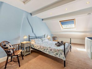 A bedroom with a sloped ceiling, a bed with a floral bedspread, a chair, a nightstand, and a radiator. - 3 Bed in Baslow (oc-pk908) (Baslow)
