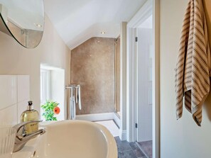 Een badkamer met een bad, een spiegel, een handdoekhouder en een douchehoek.