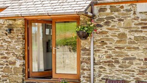 A stone building with a wooden door, steps, a hanging planter, and a bench. - 1 Bed in Looe (oc-hivie) (Lansallos)