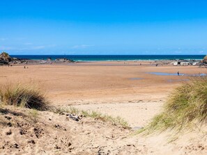 A wide sandy beach with a lighthouse in the distance, clear skies, and calm sea. - 2 Bed in Holsworthy (oc-gfoxg) (Holsworthy Hamlets)