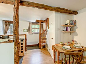A rustic kitchen with wooden beams, a dining table set for two, and a bookshelf with books. - 1 Bed in Nr Kendal (oc-lcc70) (Crosthwaite)