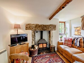 A cozy living room with a stone fireplace, a television, a sofa, and a patterned rug. - 1 Bed in Nr Kendal (oc-lcc70) (Crosthwaite)