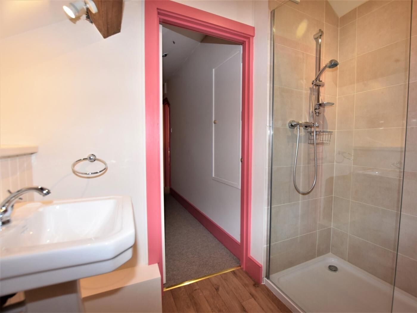 A bathroom with a shower, a sink, and a towel rack.