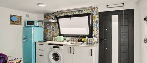 A compact kitchen with a washing machine, a microwave, and a sink.