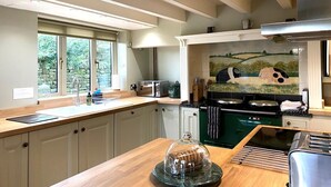 A modern kitchen with a large window, a microwave, a stove, and a tiled backsplash. - 4 Bed in Whitby (oc-g0042) (Goathland)