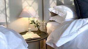 A neatly made bed with white linens, a bedside lamp, and a small table with a book and a vase of flowers. - 4 Bed in Whitby (oc-g0042) (Goathland)