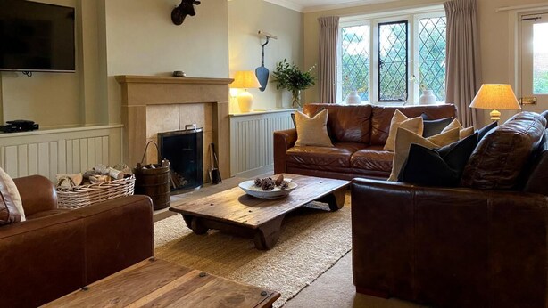 A living room with a fireplace, leather sofas, a wooden coffee table, and a television. - 4 Bed in Whitby (oc-g0042) (Goathland)