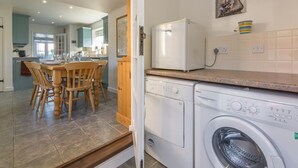 Eine Küche mit Waschmaschine, einem Esstisch mit Stühlen und einem Kühlschrank.