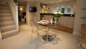 Une cuisine moderne avec une table à manger en verre, des chaises transparentes et un escalier menant à un autre niveau.