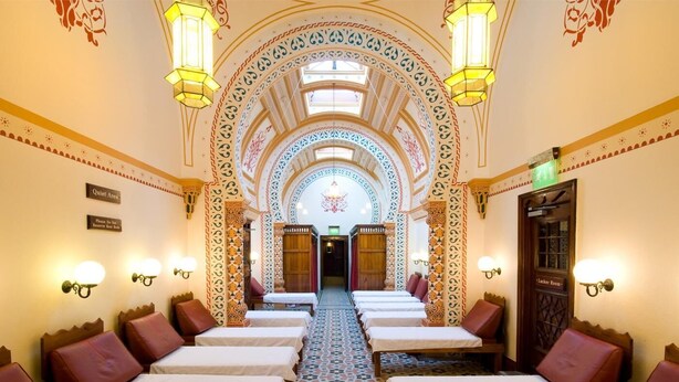 Une chambre d’hôtel avec un long couloir menant à une porte sur laquelle est inscrit « Vestiaires ».