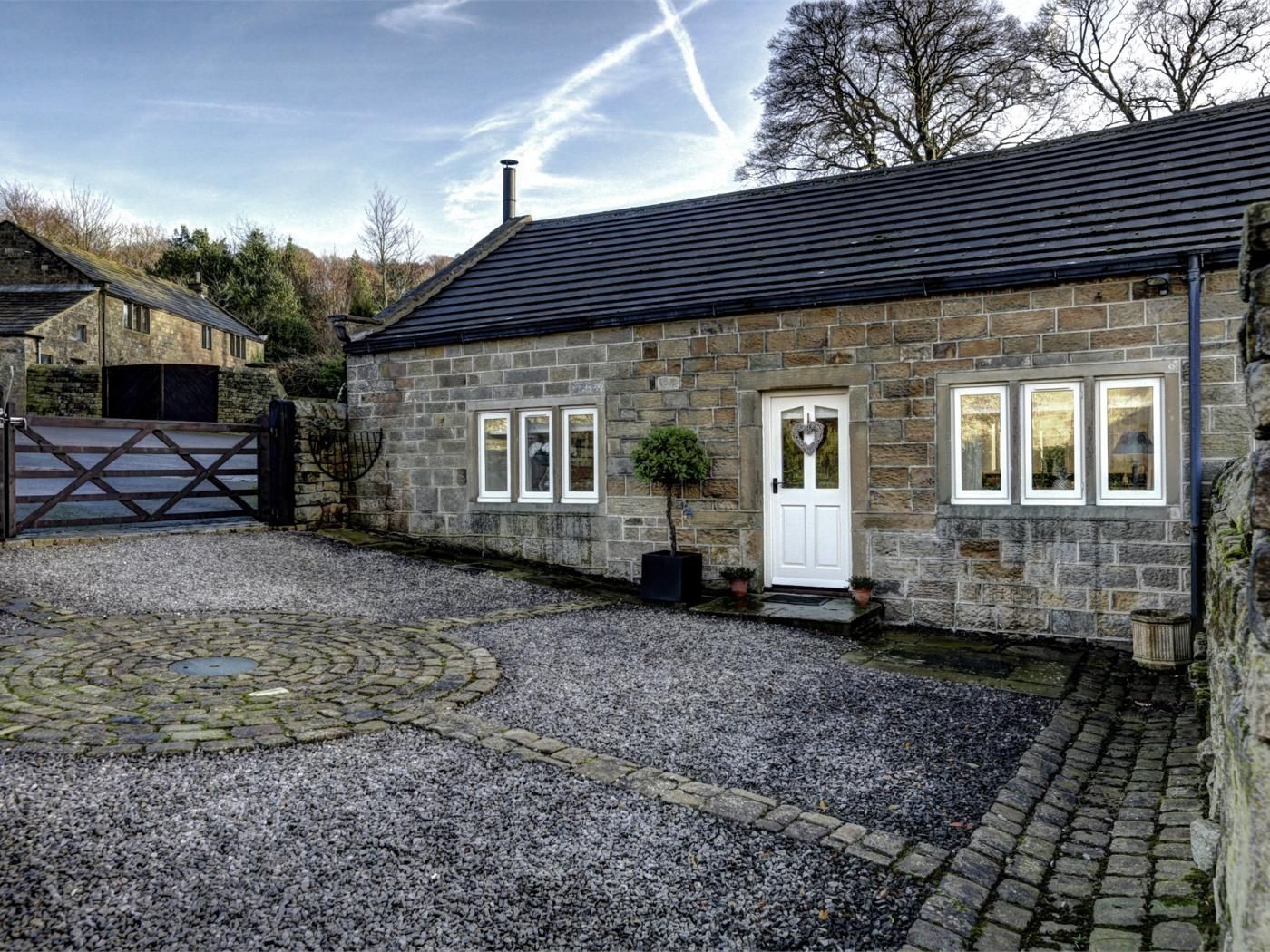 A stone building with a white door, a gravel driveway, and a stone wall.