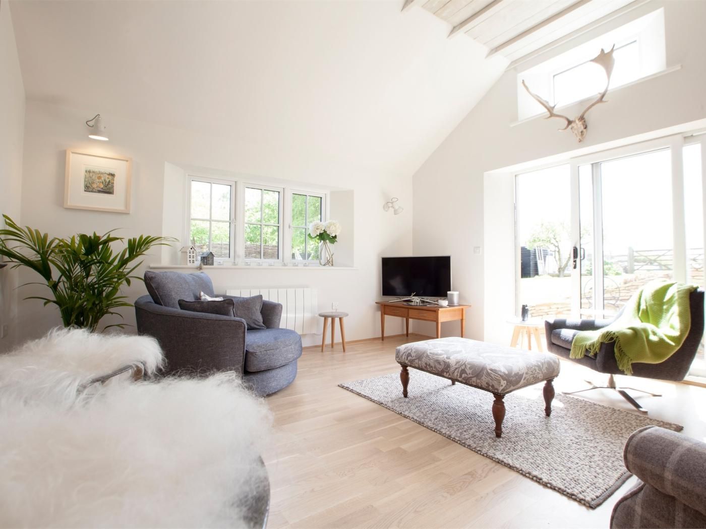 A modern living room with a grey sofa, a television, and a large window.