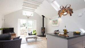 A modern living room with a fireplace, a television, and a dining area with a kitchen island. - 1 Bed in Thornton Watlass (oc-g0089) (Thornton Watlass)