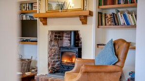 Una sala de estar acogedora con chimenea, un sillón cómodo y estanterías.